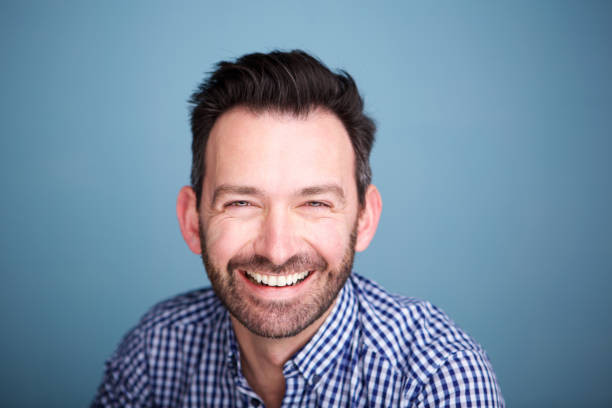istock Close up smiling man with beard against blue background 1034931478