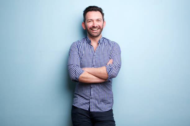 istock cheerful man with beard posing against blue wall with arms crossed 1034931490