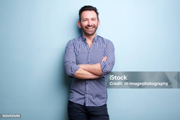 Cheerful Man With Beard Posing Against Blue Wall With Arms Crossed Stock Photo - Download Image Now