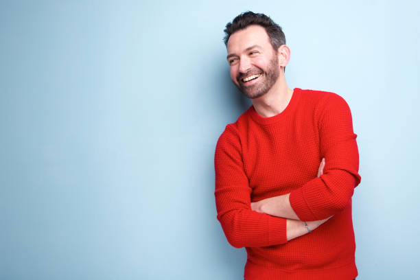 cheerful man with beard laughing against blue background Portrait of cheerful man with beard laughing against blue background garment photos stock pictures, royalty-free photos & images