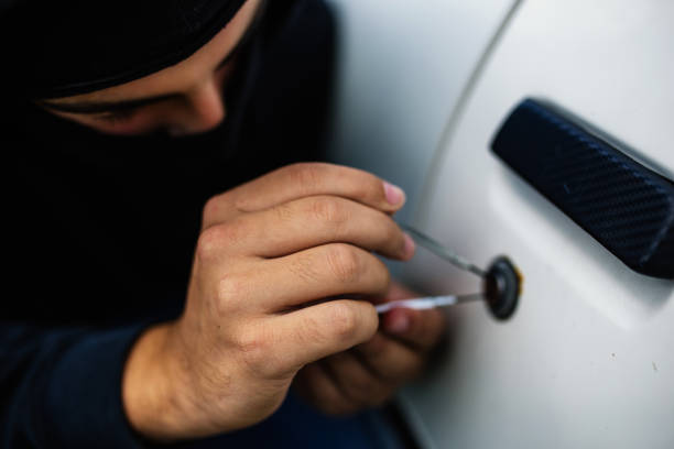 istock Masked man is trying to get into an old car 1034931984