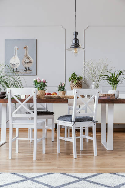 istock Patterned carpet and poster in white dining room interior with chairs at wooden table. Real photo 1034947478
