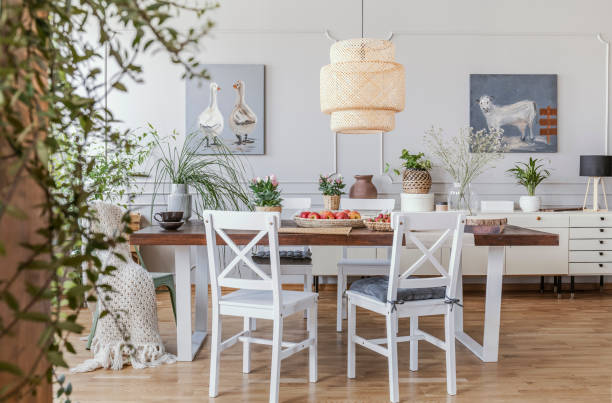istock Lamp above wooden table in rustic dining room interior with white chairs and posters. Real photo 1034947594