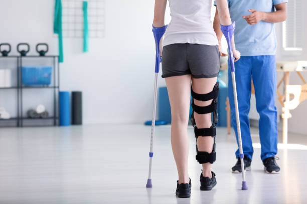 paciente con refuerzo en la pierna, caminando con muletas durante la rehabilitación - columna vertebral humana fotos fotografías e imágenes de stock