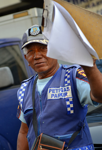 Local trafficpolice and parking officer by his vehicle on a sunny day in Jakarta, Indonesia