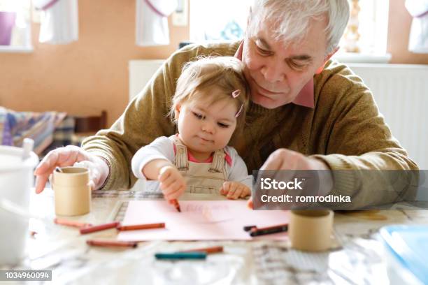 Süße Kleine Baby Kleinkind Mädchen Und Gut Aussehend Senior Großvater Malerei Mit Bunten Bleistiften Zu Hause Enkelkind Und Man Gemeinsam Spaß Haben Stockfoto und mehr Bilder von Kind