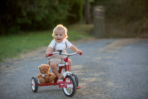 mignon bébé enfant, garçon, jouer avec tricycle dans cour sur coucher de soleil - tricycle photos et images de collection