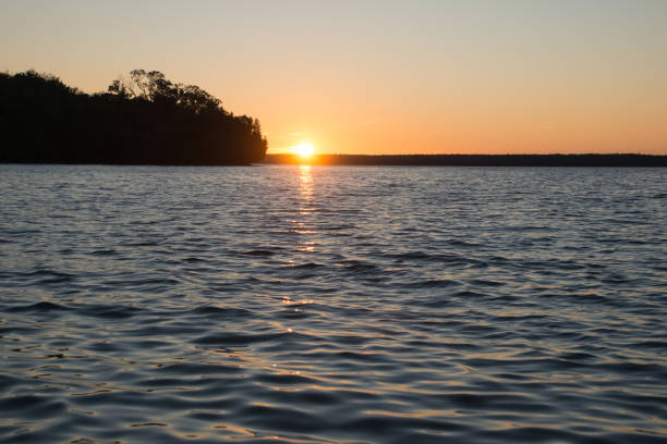Lake Manitou shoreline sunset landscape with cedar trees and orange sky