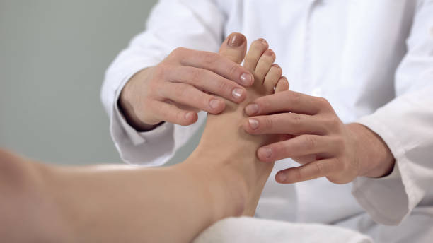 Traumatologist examining patient foot, rehabilitation procedures, leg fracture stock photo