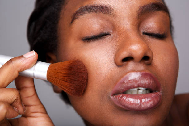 istock Close up attractive woman applying makeup with brush for beautiful complexion 1034983240