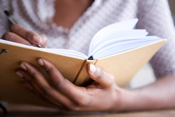 istock Close up female hands holding pen and book 1034985936