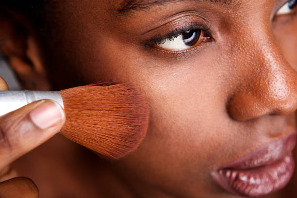 istock Close up beautiful woman applying makeup with brush for smooth matte finish 1034986084