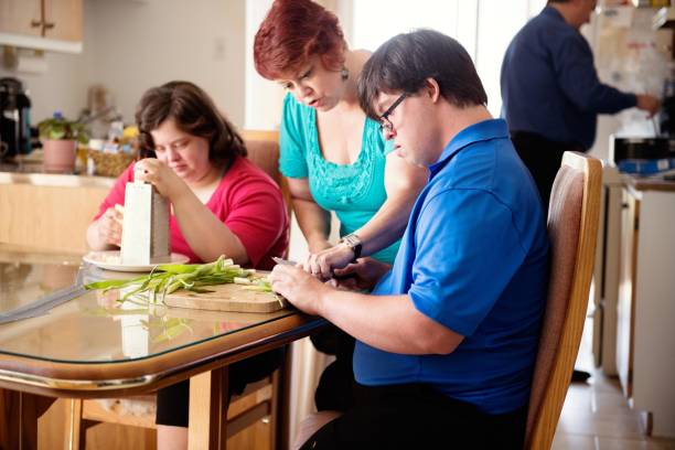 Couple with Down Syndrome learning cooking cutting vegetables stock photo