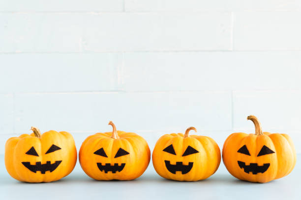 istock Stack of yellow ghost pumpkin on white brick block background. halloween concept. 1034988594