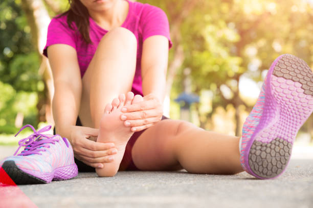 young woman massaging her painful foot from exercising and running sport and excercise concept. - physical injury imagens e fotografias de stock