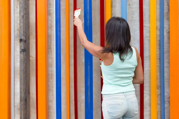 Concept design thinking and creative ideas. The girl paints a colorful wooden wall.