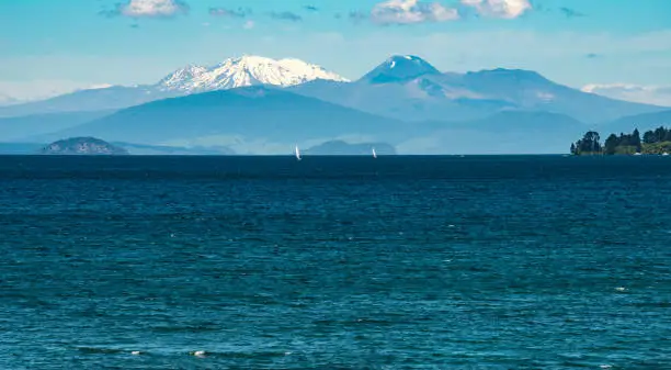 Photo of The landscape of great lake Taupo the largest freshwater lake in New Zealand with the volcanic landscape of Tongariro national park at the background.