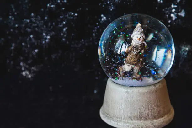 Photo of Glass ball with snow and snowflake on dark background