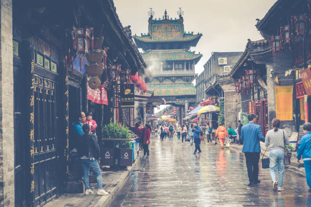 tourists and local people in the ancient city of Pingyao in central China, Asia. Rainy weather. PINGYAO, CHINA - MAY 21, 2018: Tourists and local people in the ancient city of Pingyao in central China, Asia. Rainy weather. phenix stock pictures, royalty-free photos & images