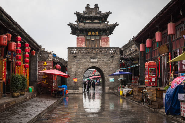 Tourists and local people in the ancient city of Pingyao in central China, Asia. Rainy weather. PINGYAO, CHINA - MAY 21, 2018: Tourists and local people in the ancient city of Pingyao in central China, Asia. Rainy weather. phenix stock pictures, royalty-free photos & images