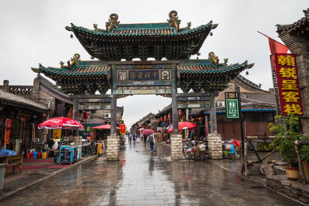 Tourists and local people in the ancient city of Pingyao in central China, Asia. Rainy weather. PINGYAO, CHINA - MAY 21, 2018: Tourists and local people in the ancient city of Pingyao in central China, Asia. Rainy weather. phenix stock pictures, royalty-free photos & images