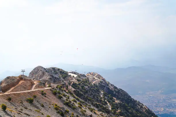 Photo of Mountain Babadag is ideal place for paragliding and some paragliders flying on the mountain and Fethiye city and Mediterranean sea in background