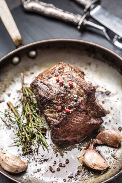 istock Juicy beef steak with spices and herbs in old pan 1035019718