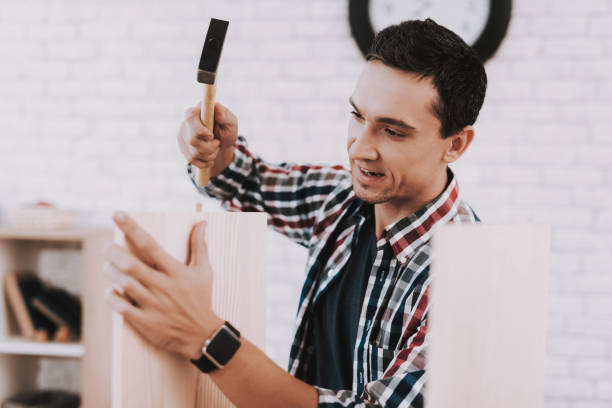 istock Young Man Assembling Wooden Bookshelf at Home. 1035021482