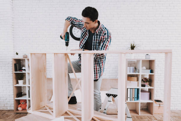 istock Young Man Assembling Wooden Bookshelf at Home. 1035021908