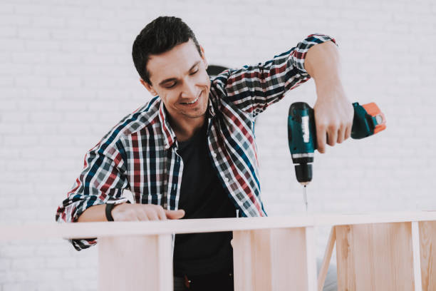 istock Young Man Assembling Wooden Bookshelf at Home. 1035021944