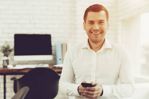 istock Smiling Young Man with Mobile Phone in Office. 1035026156