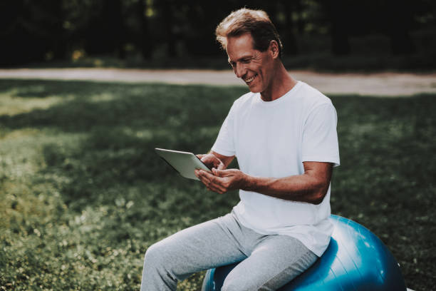 istock Man Sitting on Ball for Yoga and Using Tablet. 1035027424