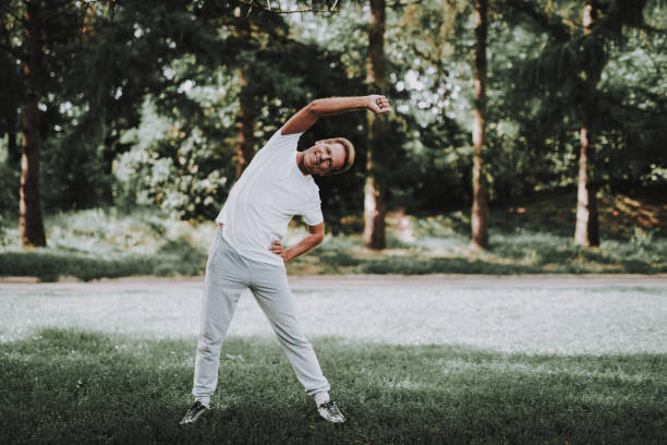 istock Man in White Sportswear Doing Exercises in Park. 1035027542