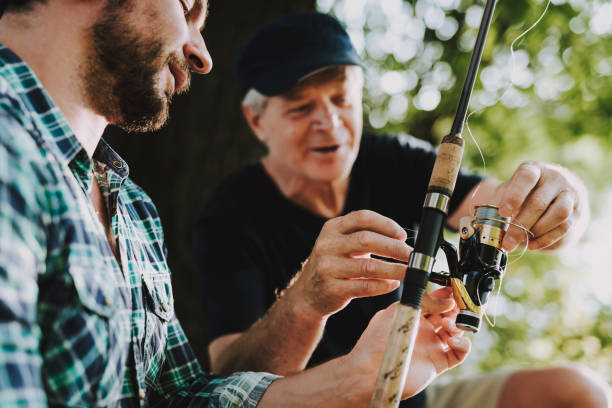 istock Old Father with Bearded Son Fishing on River. 1035027790