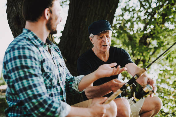 istock Old Father with Bearded Son Fishing on River. 1035027922