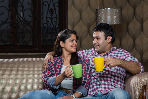 istock Cheerful young beautiful couple having coffee together on sofa - Stock image 1035030762