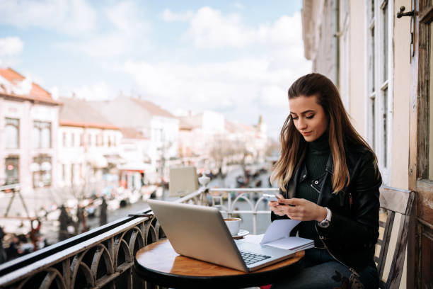 istock Student girl studying outdoors at a cafe. Taking a break using phone and drinking coffee. 1035038584