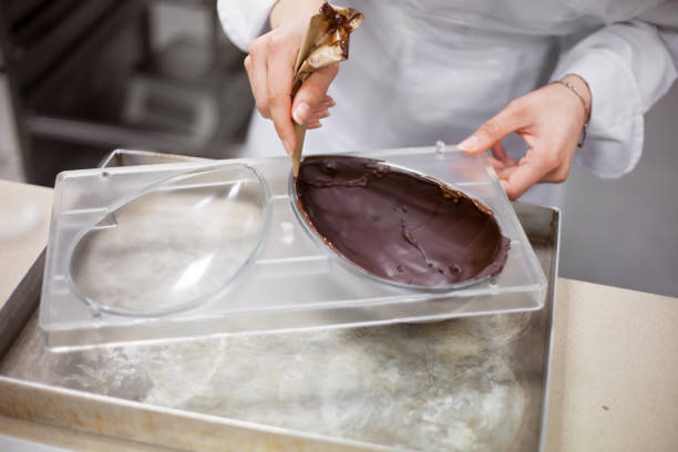 Making chocolate. Chocolate factory. Making chocolate. Making chocolate easter eggs. Chocolate factory. egg molds stock pictures, royalty-free photos & images