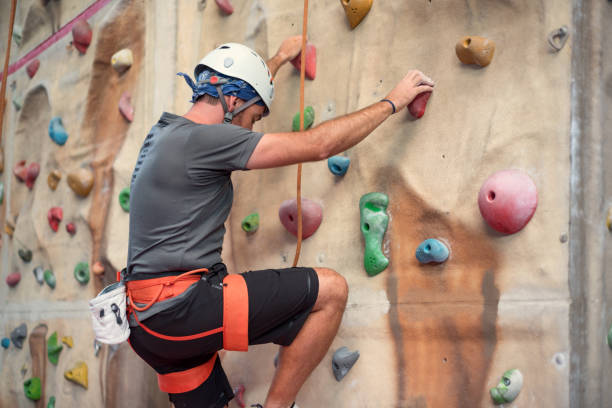 Young man practicing rock climbing on artificial wall indoors. Young man practicing rock climbing on artificial wall indoors. crag stock pictures, royalty-free photos & images