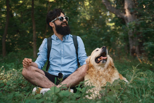 istock Man resting on the grass sitting crossed legs with his dog 1035054056
