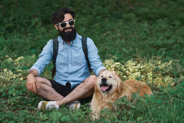 istock Man resting on the grass sitting crossed legs with his dog 1035054088