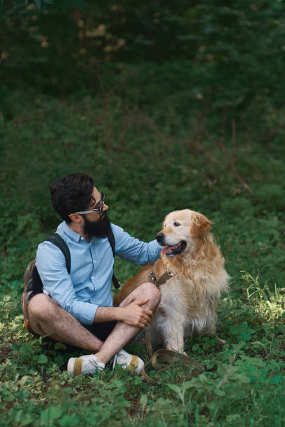 istock Man resting on the grass sitting crossed legs with his dog 1035054178