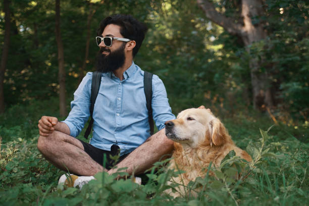 Man resting on the grass sitting crossed legs with his dog