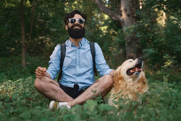 istock Man resting on the grass sitting crossed legs with his dog 1035054558