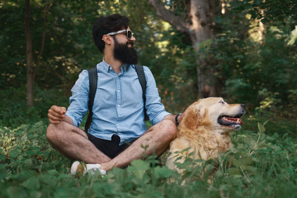 istock Man resting on the grass sitting crossed legs with his dog 1035056100