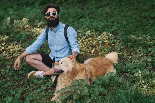 istock Man resting on the grass sitting crossed legs with his dog 1035056728