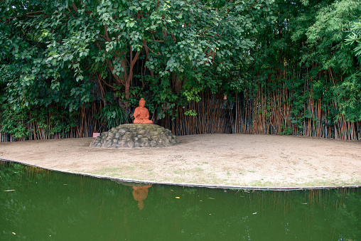 Red Buddha statue siting under Bodhi tree