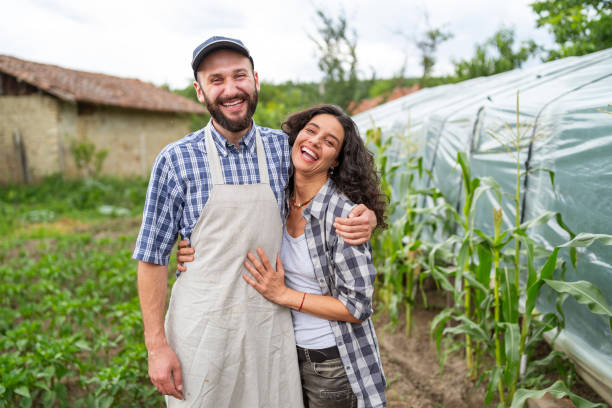 Couple farmers embracing in greenhouse Cheerful farmers embracing and standing in greenhouse the farmer and his wife pictures stock pictures, royalty-free photos & images