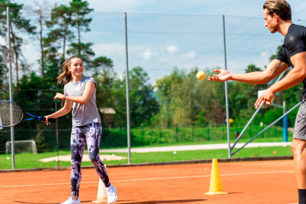istock Young man teaching a girl playing tennis 1035072768