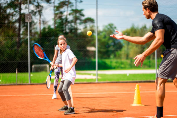 Young man teaching two girls playing tennis